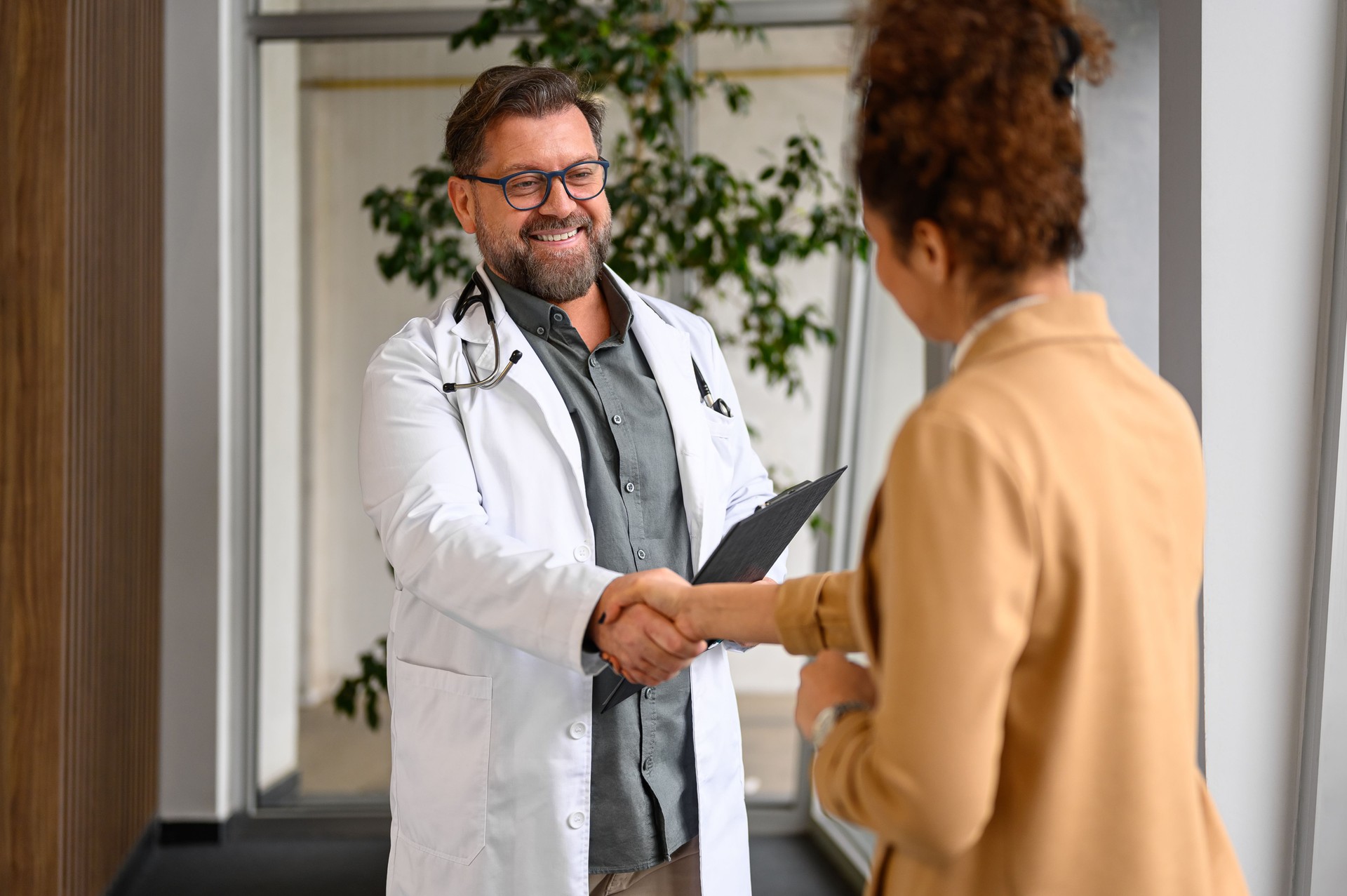 Smiling doctor shaking hands with female patient in a medical clinic