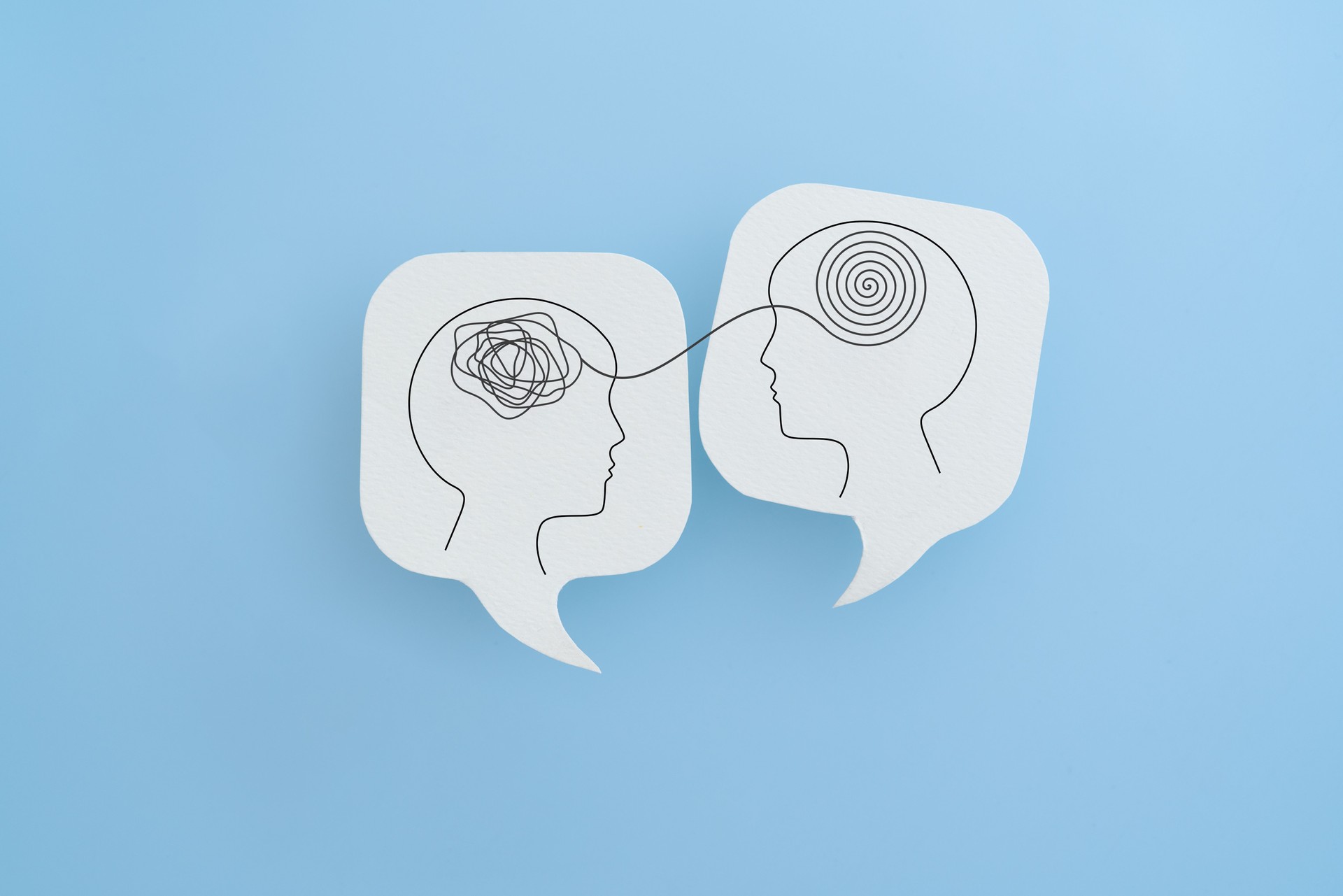 Two speech bubbles with brain illustrations showing complex medical information becoming clear communication